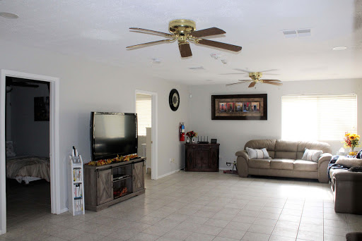 A spacious and modern living room featuring a comfortable couch, a TV setup, and ceiling fans.