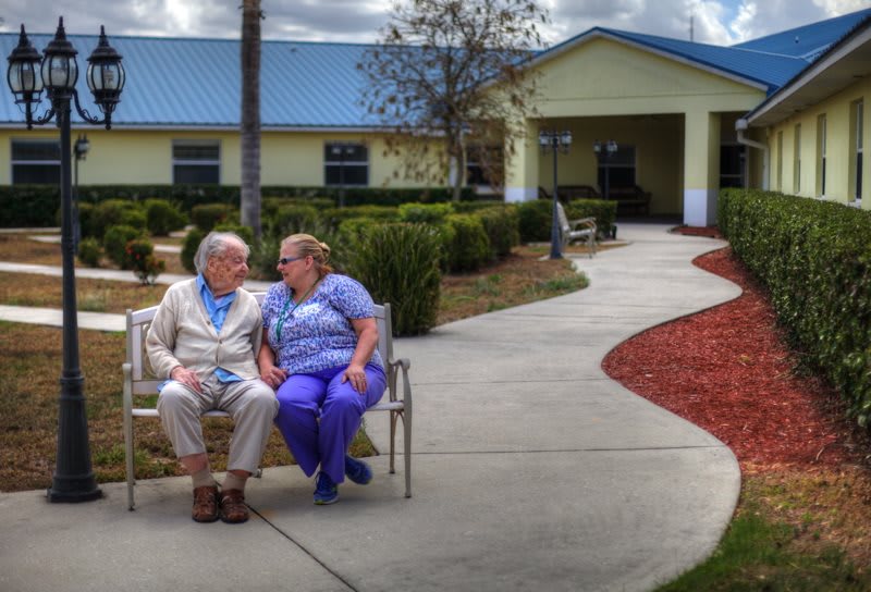 Elderly couple sitting on a bench in the garden of a nursing home.