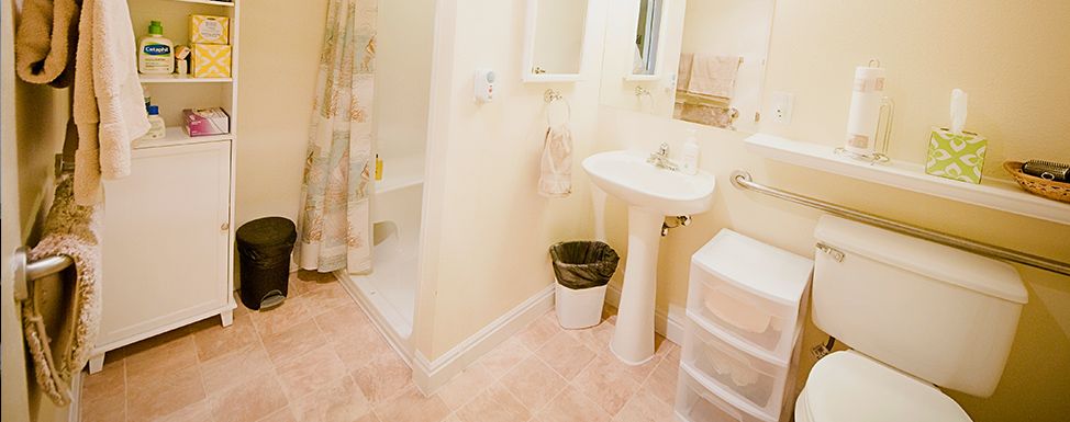 A clean and organized bathroom with a shower, sink, and mirror.