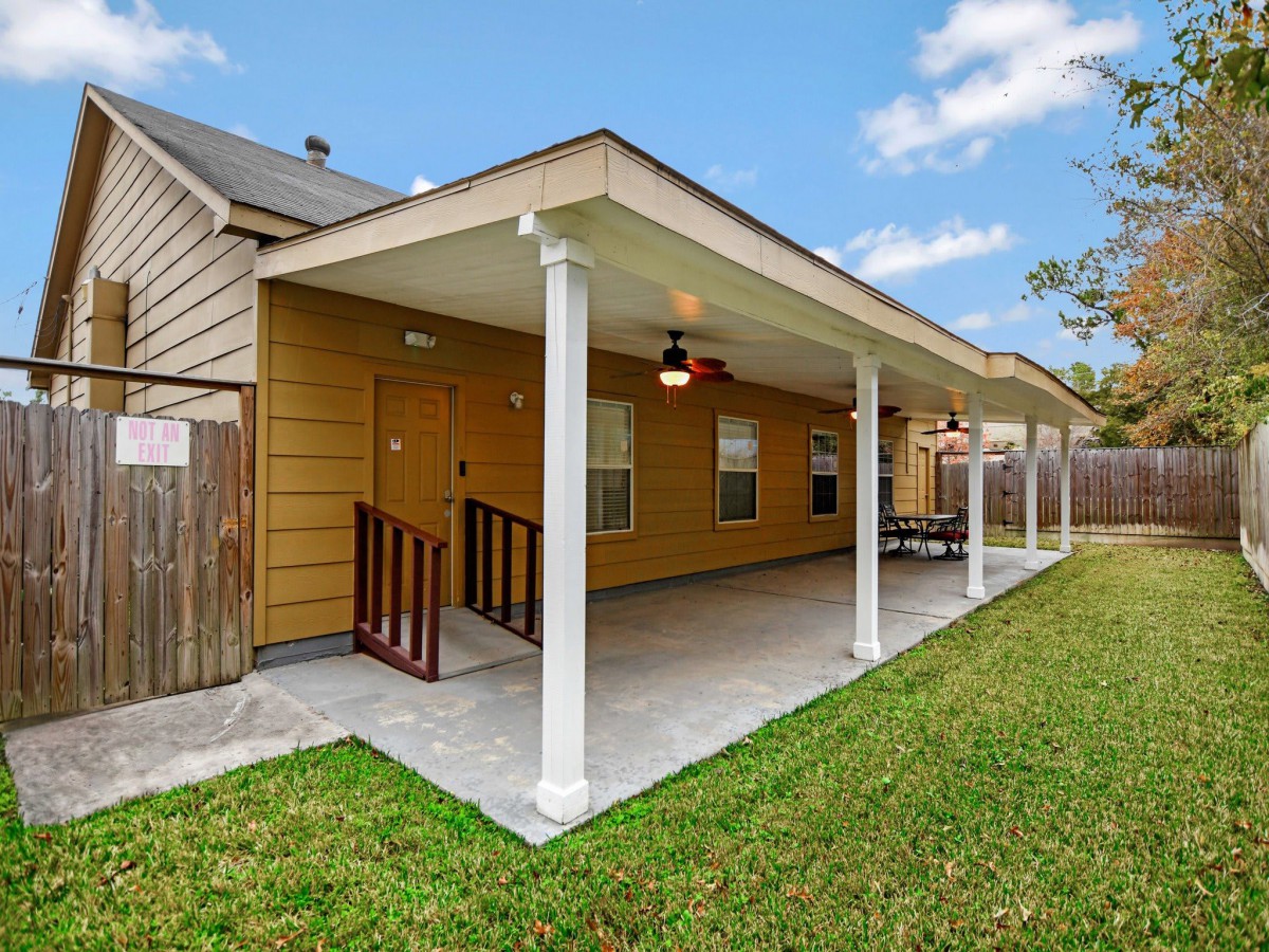 A spacious covered patio in a backyard with a neatly manicured lawn.
