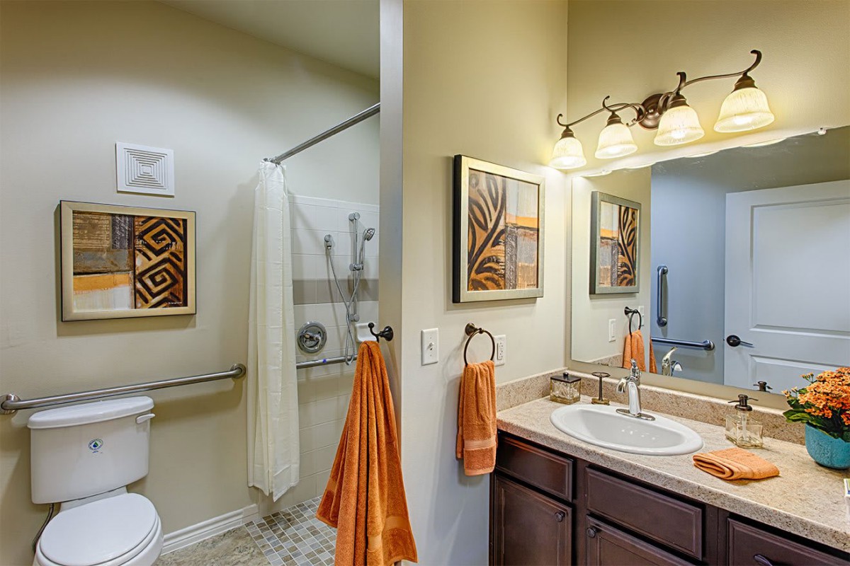A well-decorated bathroom with a shower, sink, and warm lighting.