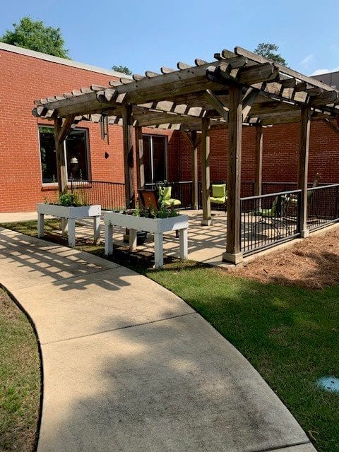 An outdoor patio area with a pergola, seating, and landscaped walkway.