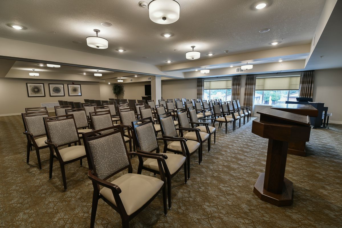 A well-lit conference room with rows of chairs and a podium, ready for a meeting or presentation.