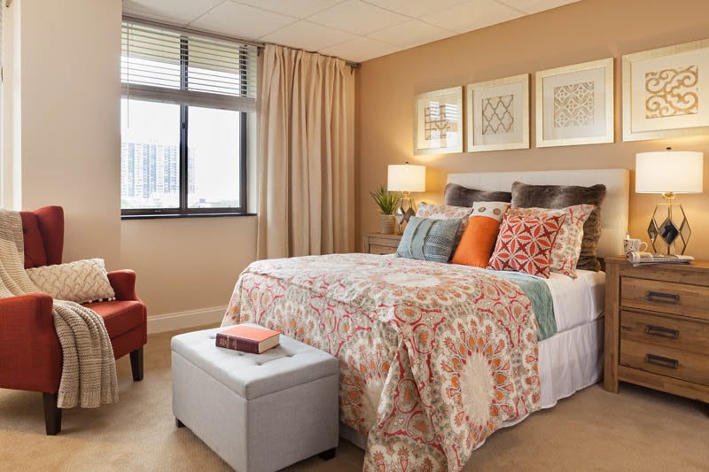 A cozy and modern bedroom with a patterned bedspread, colorful cushions, and elegant decor.