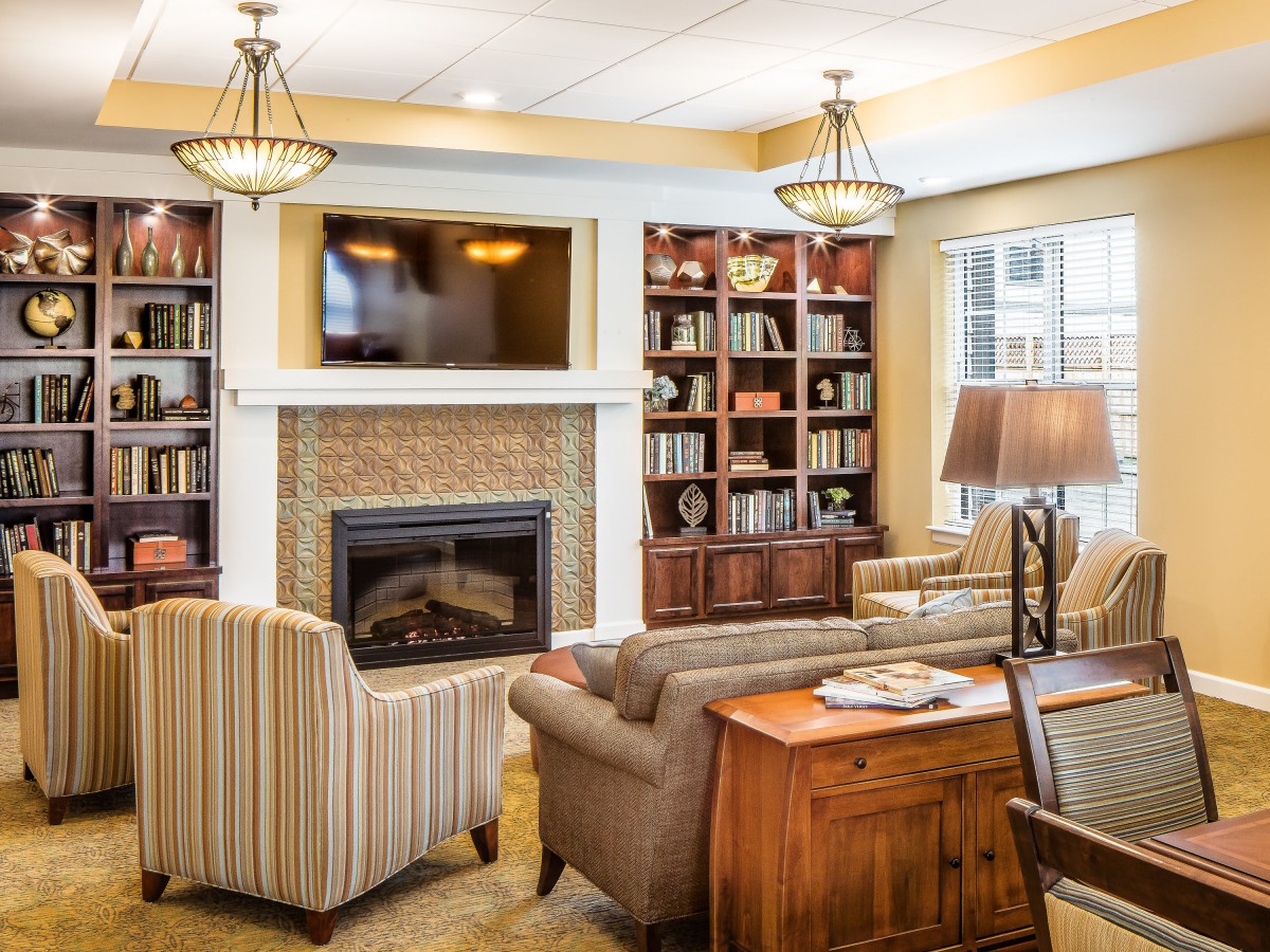 A cozy living room with a fireplace, bookshelves, and comfortable seating.
