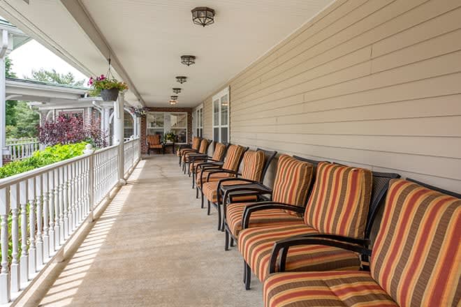 A long porch with a row of chairs featuring striped cushions, offering inviting outdoor seating.