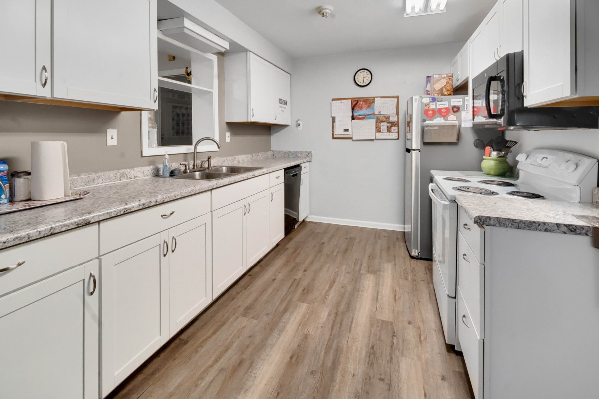 A modern kitchen with white cabinets and wood flooring.