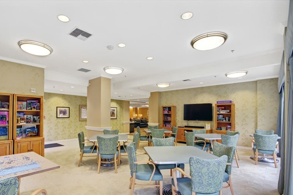 A community room with tables, chairs, a television, and bookshelves.