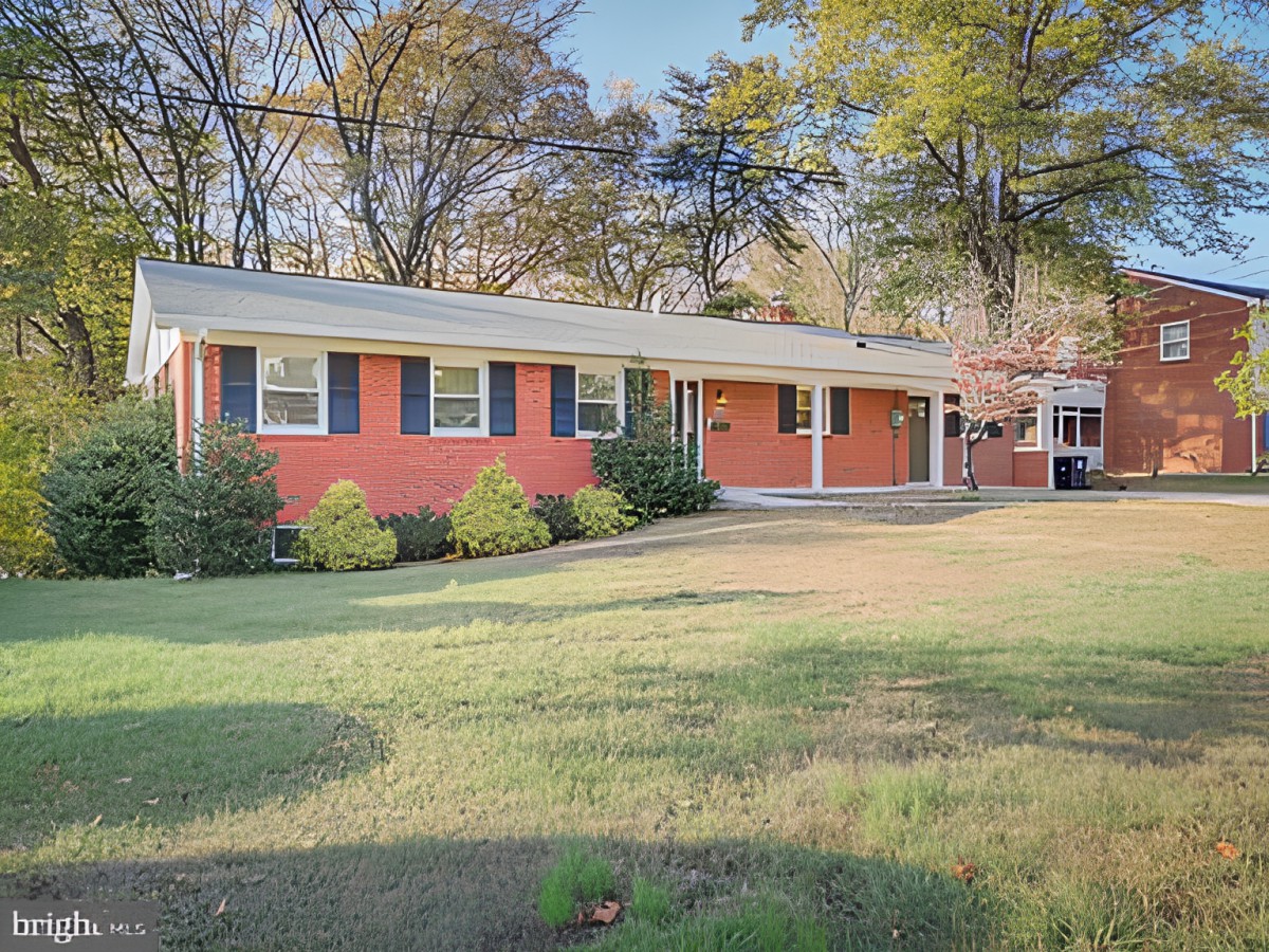 A single-story brick ranch-style house with a spacious front yard and trees in the background.