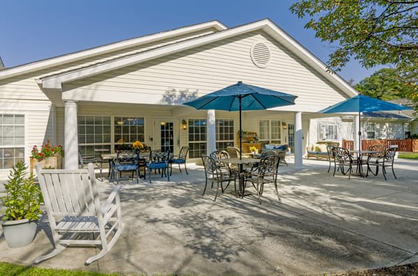 An outdoor patio area with tables and chairs under blue umbrellas on a sunny day.