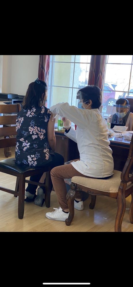 A healthcare professional is administering a vaccine to a seated patient in an indoor setting.