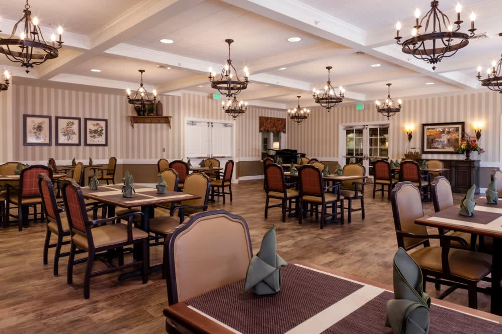 An elegant dining room with neatly arranged tables and chandeliers.