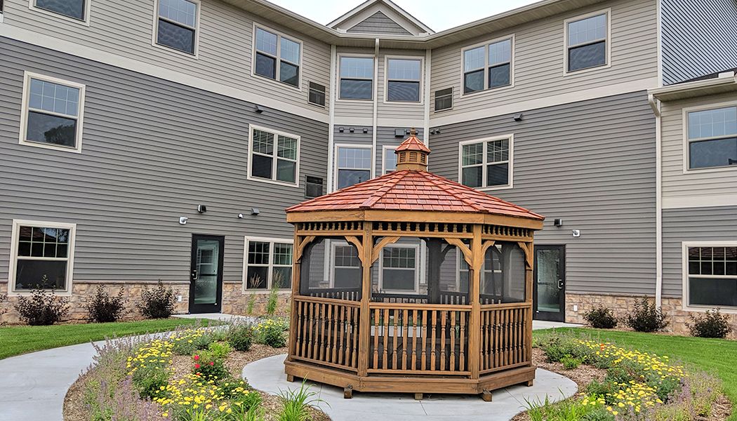 A wooden gazebo situated in the courtyard of a residential building.