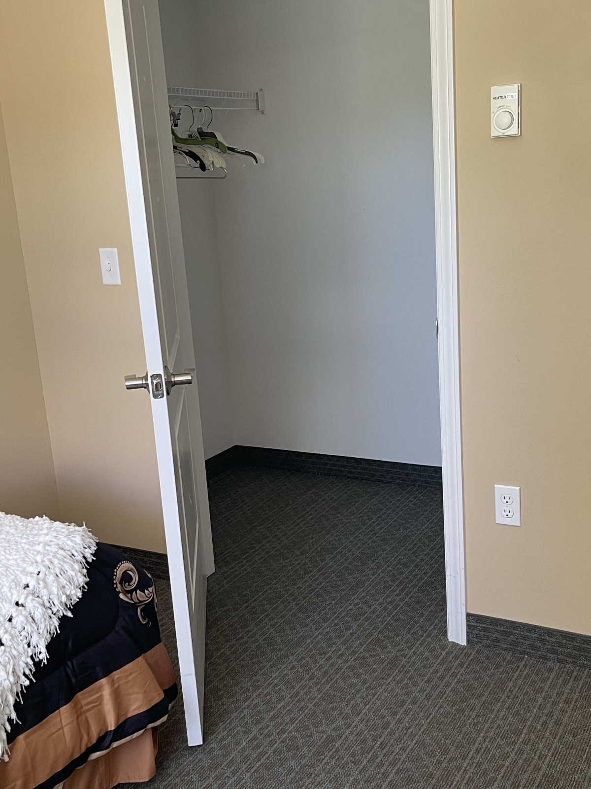 An empty room with an open closet door and hangers inside.
