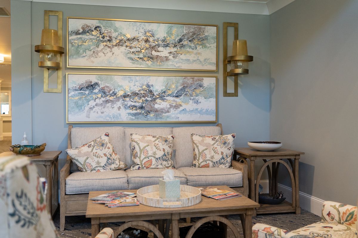 A cozy living room with a neutral color palette, featuring a comfortable sofa adorned with patterned cushions, a wooden coffee table, and abstract wall art.
