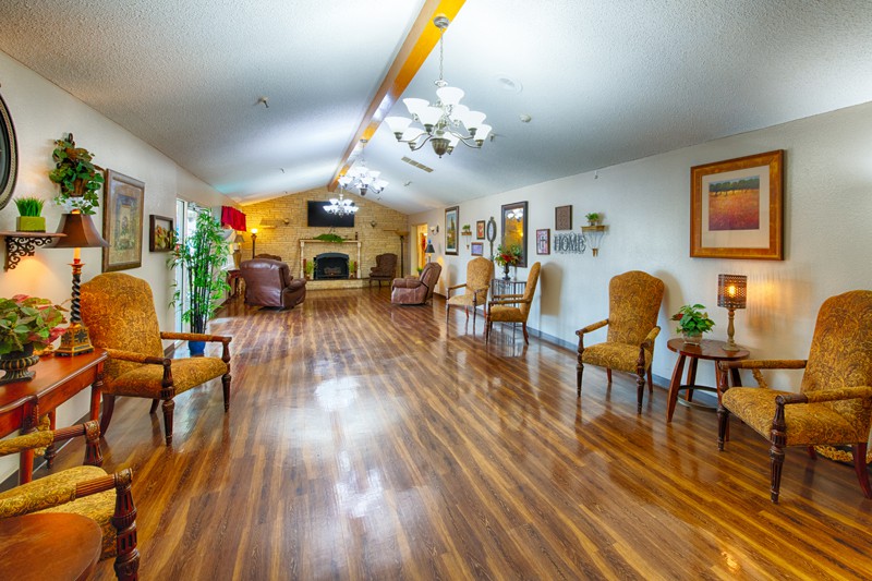 A spacious living room with wooden flooring, comfortable seating, and elegant decor.