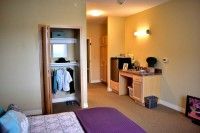 A cozy bedroom featuring a wardrobe, dresser, and soft lighting.