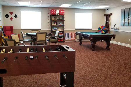 A cozy game room featuring a foosball table, a pool table, and various board games.
