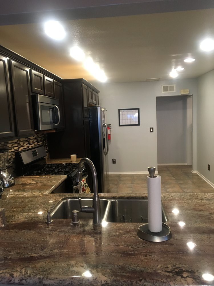 A modern kitchen with dark wood cabinets, stainless steel appliances, and granite countertops.