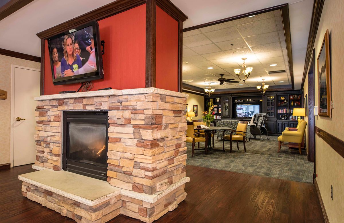 A cozy lounge area featuring a stone fireplace and a wall-mounted television, with modern decor and seating.