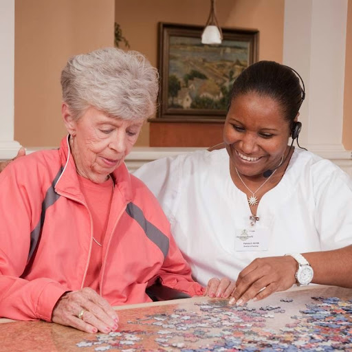 A caregiver and an elderly woman enjoy quality time together as they work on a puzzle.
