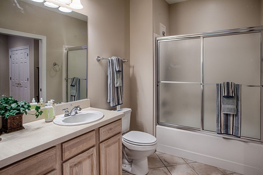 A clean and modern bathroom featuring a sink with a mirror, a toilet, and a shower with glass doors.