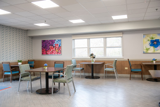 A spacious dining area featuring modern tables and chairs, complemented by vibrant artwork and ample natural light.