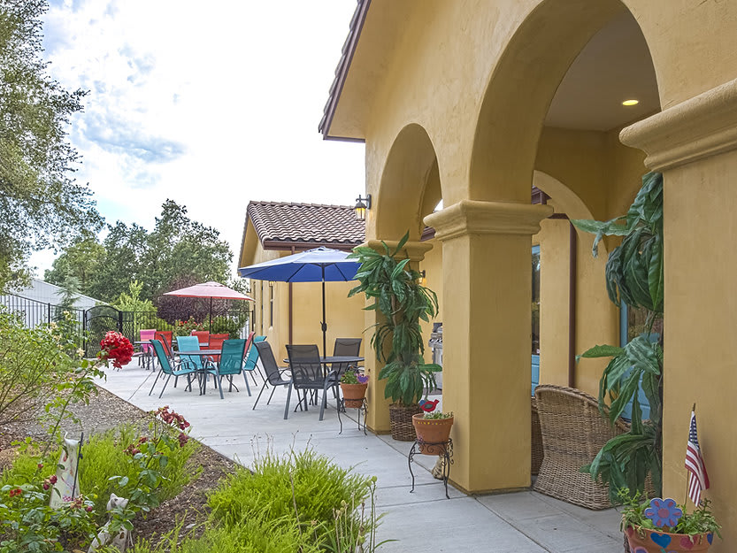 A sunny outdoor patio featuring colorful umbrellas and seating next to a yellow building.