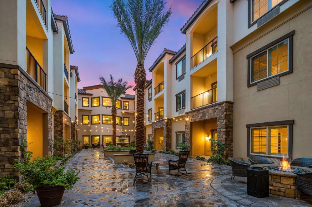 A modern apartment complex courtyard with palm trees and evening lighting.