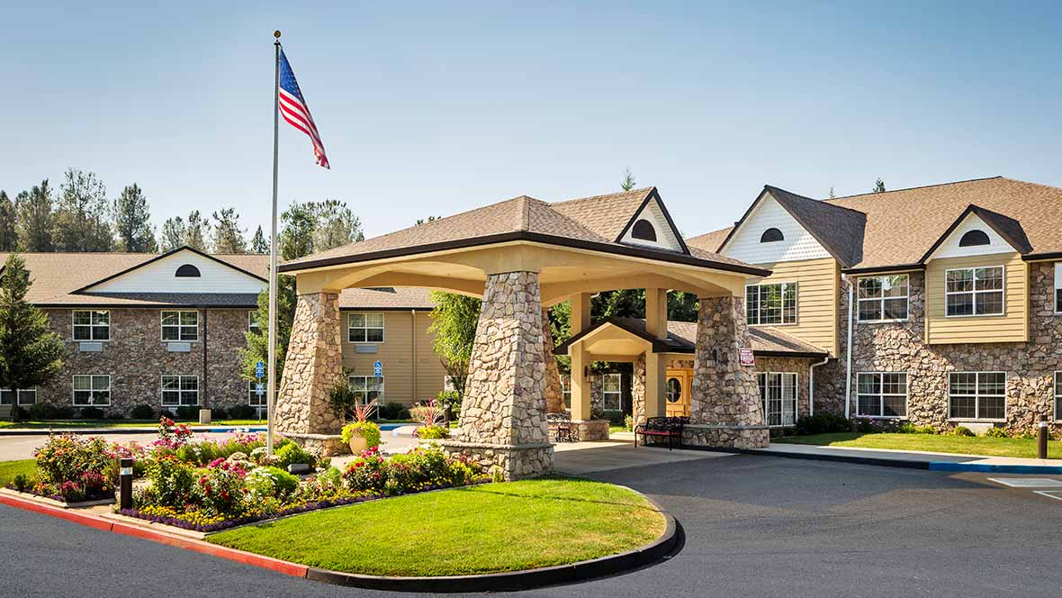 A well-maintained building entrance with stone pillars and an American flag.