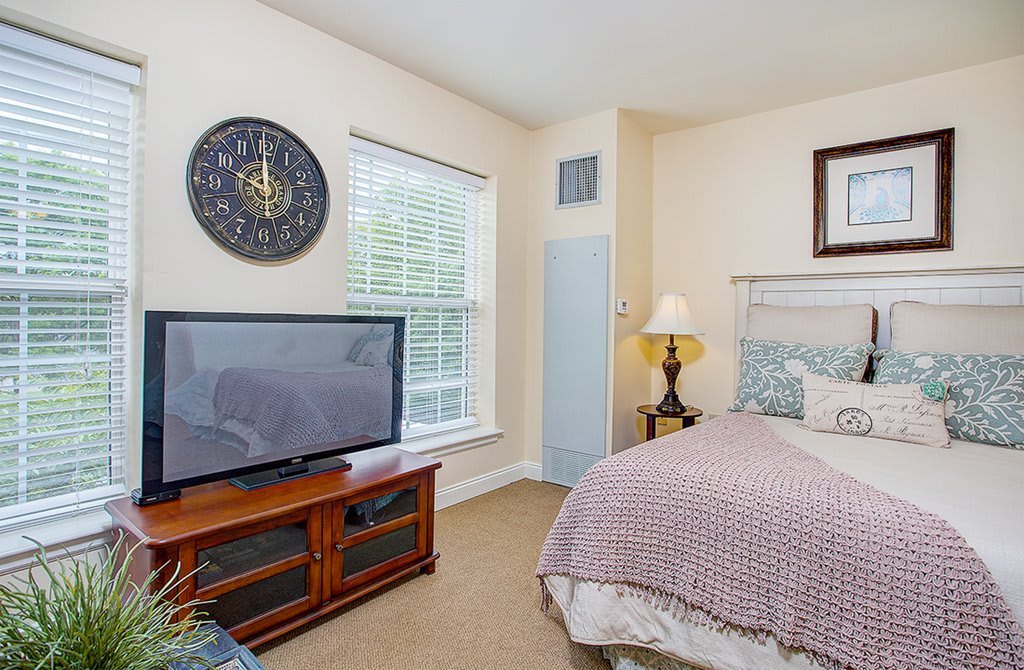 A cozy bedroom with a bed, television, and a decorative lamp.