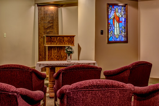 A serene interior view of a church featuring comfortable seating and a beautiful stained glass window.