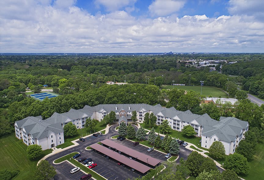 Aerial view of an apartment complex surrounded by lush greenery under a partly cloudy sky.