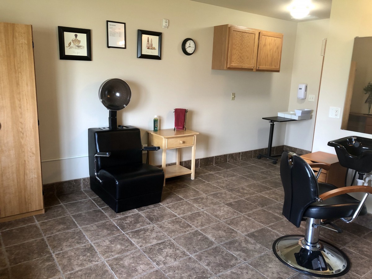 A cozy and well-organized hair salon interior with styling chairs and a dryer.