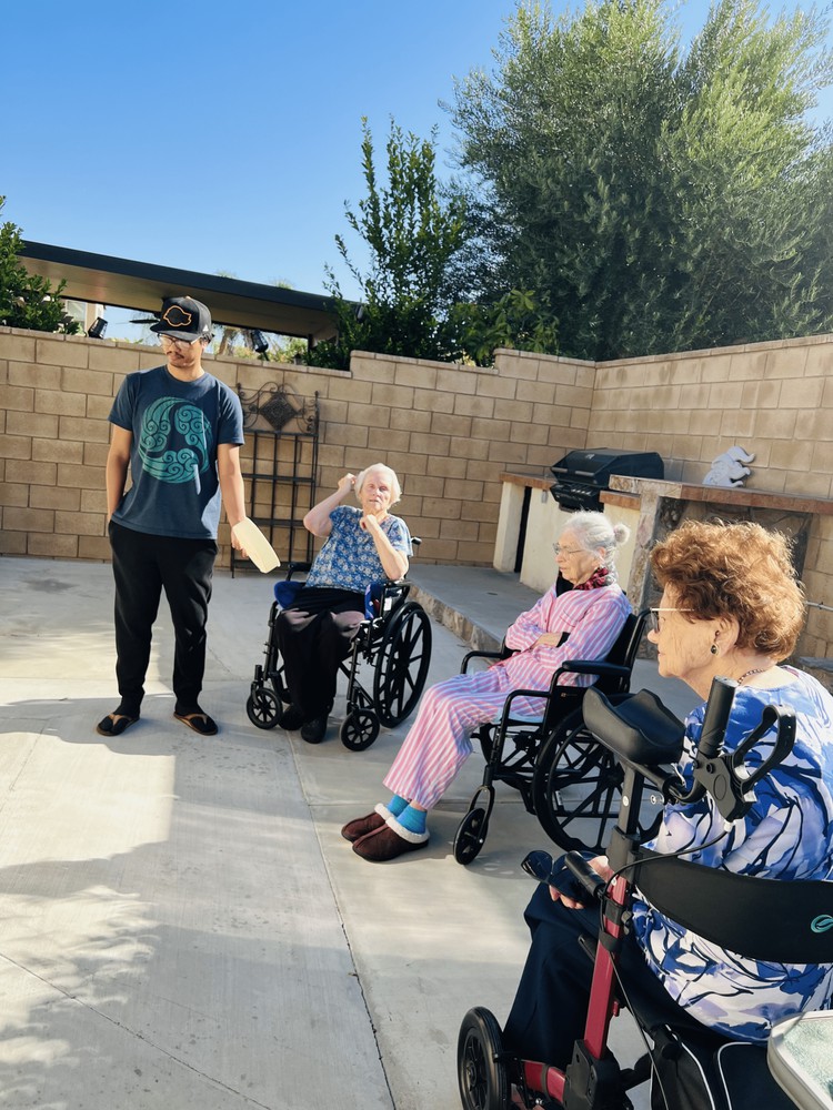 A group of people, some in wheelchairs, enjoying a sunny day outdoors.