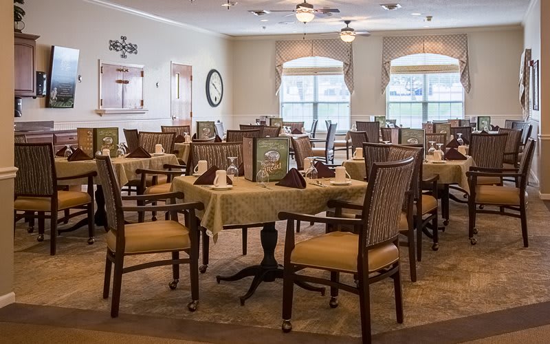 A cozy dining area with neatly arranged tables and chairs, featuring elegant decor and natural lighting.