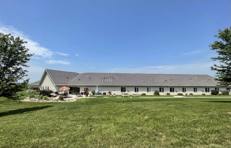 A long, single-story building with a well-maintained grassy area in front under a clear blue sky.