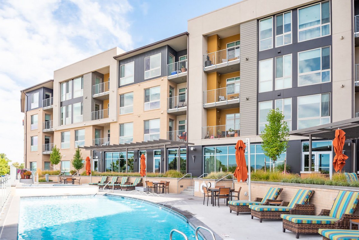 A modern residential apartment building with a swimming pool and outdoor seating area.