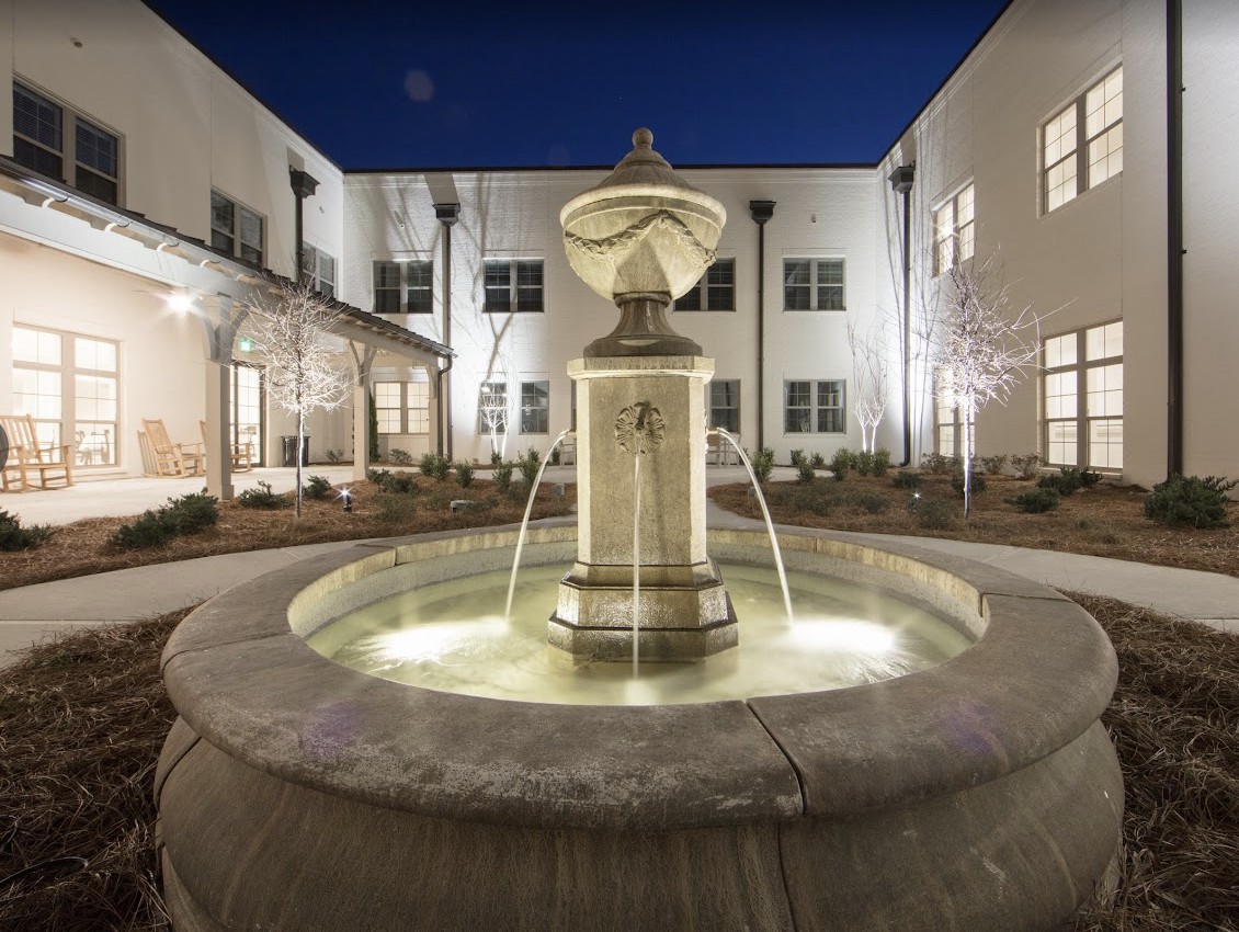 A beautifully lit fountain in the courtyard of a modern building at night.