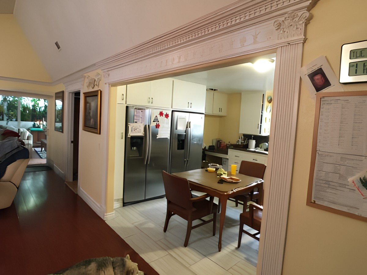A cozy kitchen with a dining area, featuring a refrigerator and a small table with chairs.