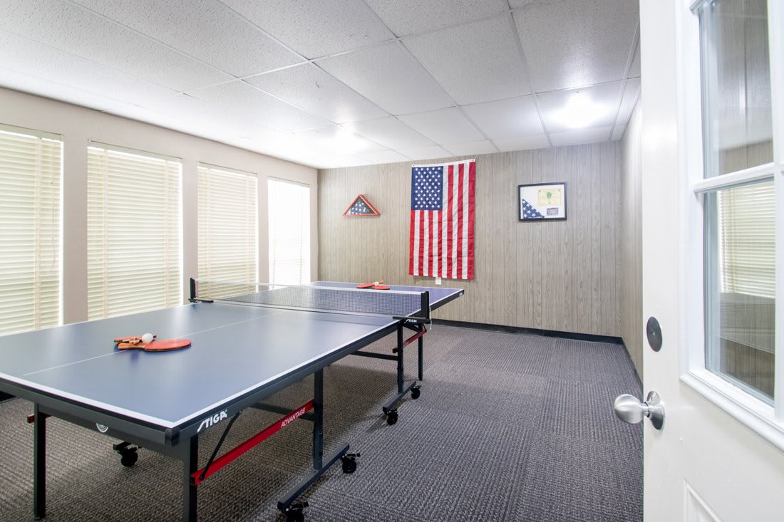 A recreational game room featuring a ping pong table and an American flag on the wall.