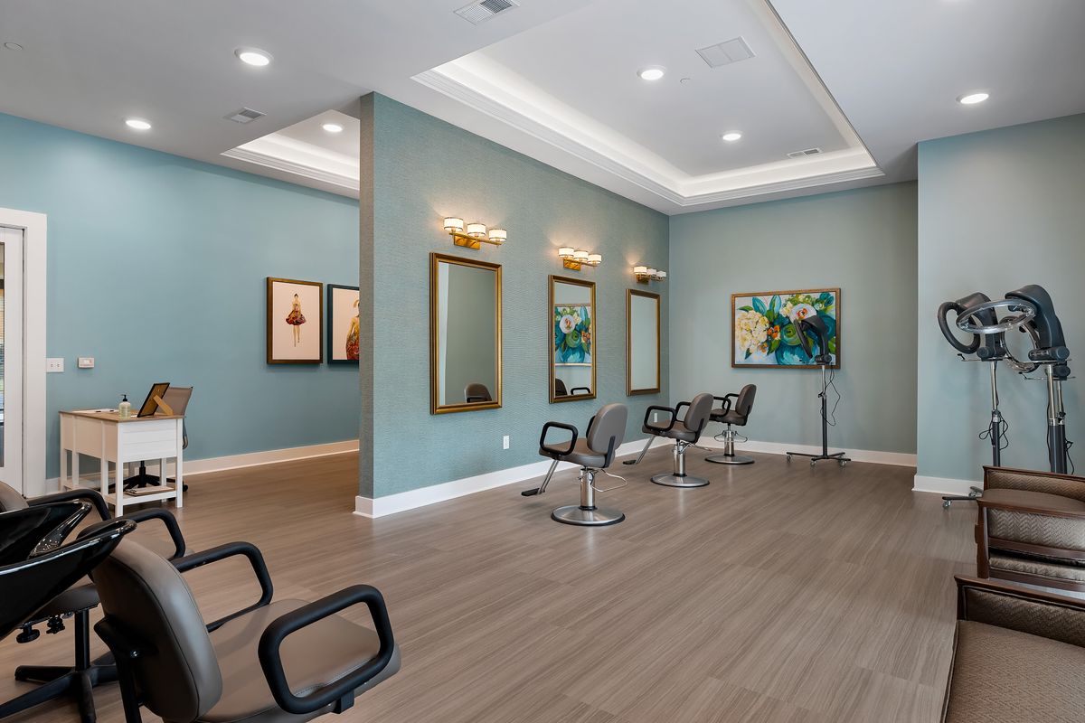 A modern salon interior featuring sleek chairs, large mirrors, and stylish artwork on blue walls.