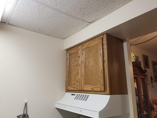 View of a kitchen with wooden cabinets and a range hood.