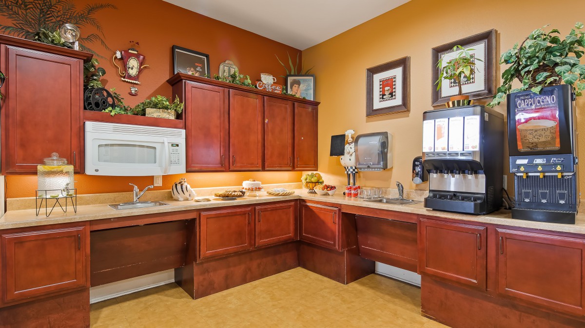 A cozy kitchen area with wooden cabinets, a microwave, and coffee maker, adorned with wall decor and framed pictures.