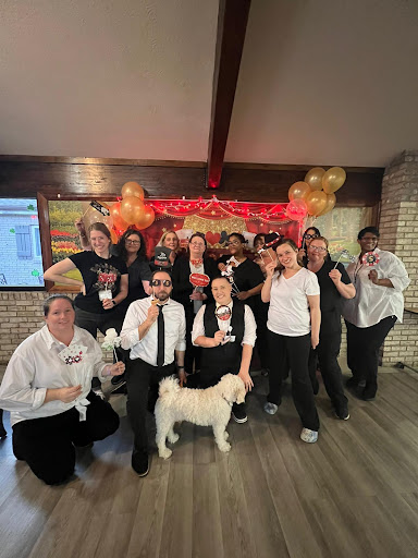 A joyful gathering of the team celebrating a special occasion, complete with balloons and a furry friend!