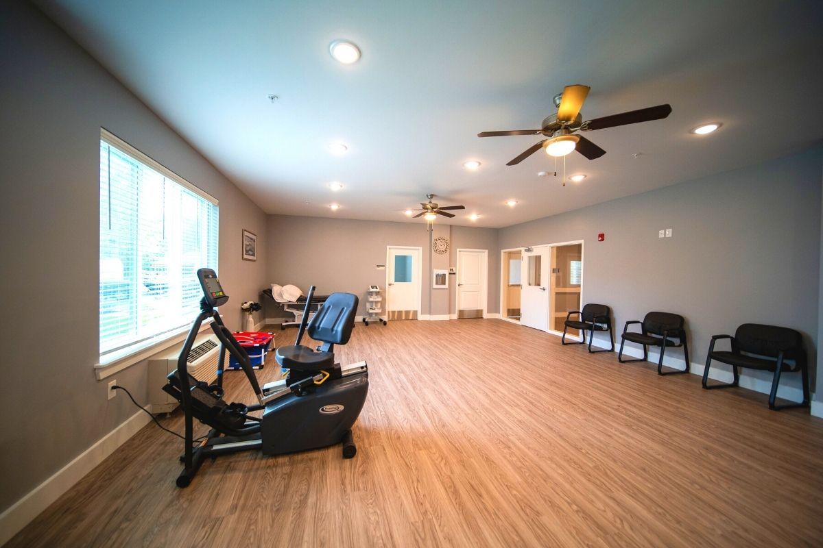 A spacious exercise room with a stationary bike and seating area.