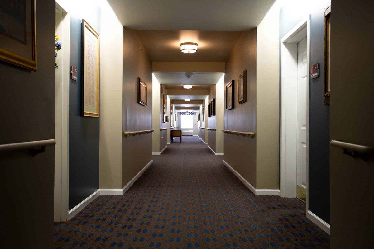 A long, empty hallway with carpeting and warm lighting.