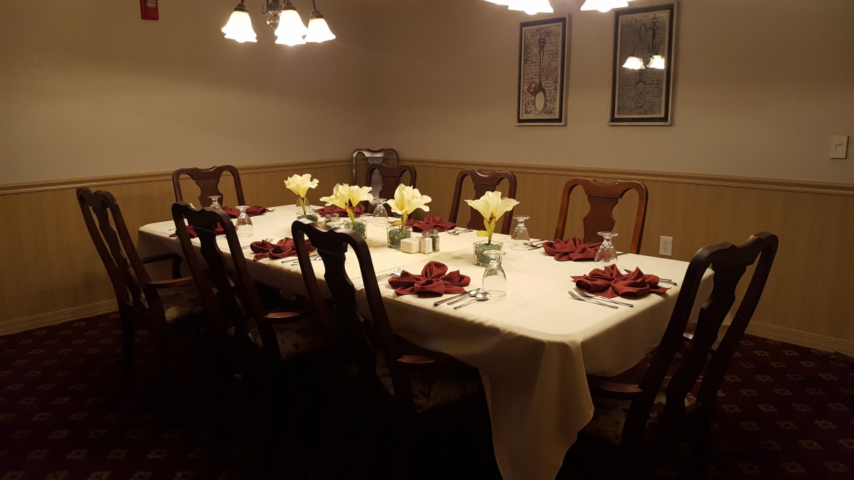 A warmly lit dining room with a beautifully set table, adorned with flowers and elegant decor.