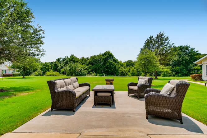 A cozy outdoor patio setup with comfortable seating overlooking a lush, green landscape.