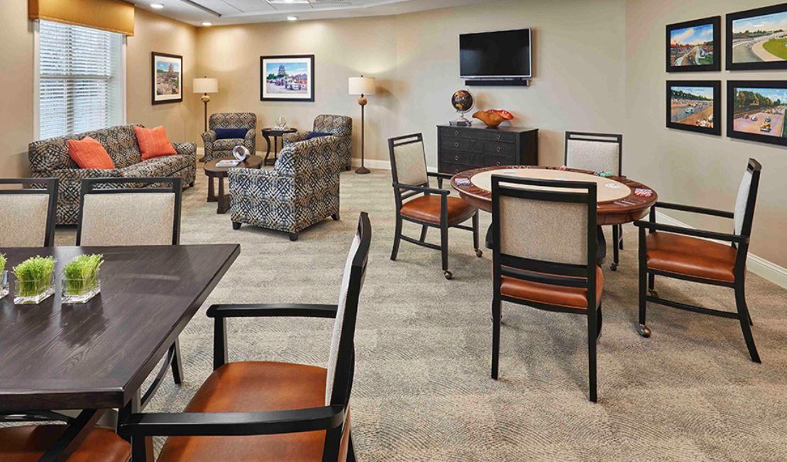 A comfortable lounge area with chairs, tables, and a television.